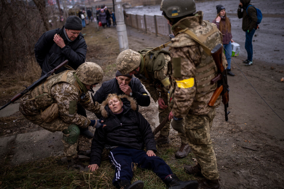 Ukrainska soldater tar hand om en kvinna som försöker ta sig ut ur Kiev under lördagen.