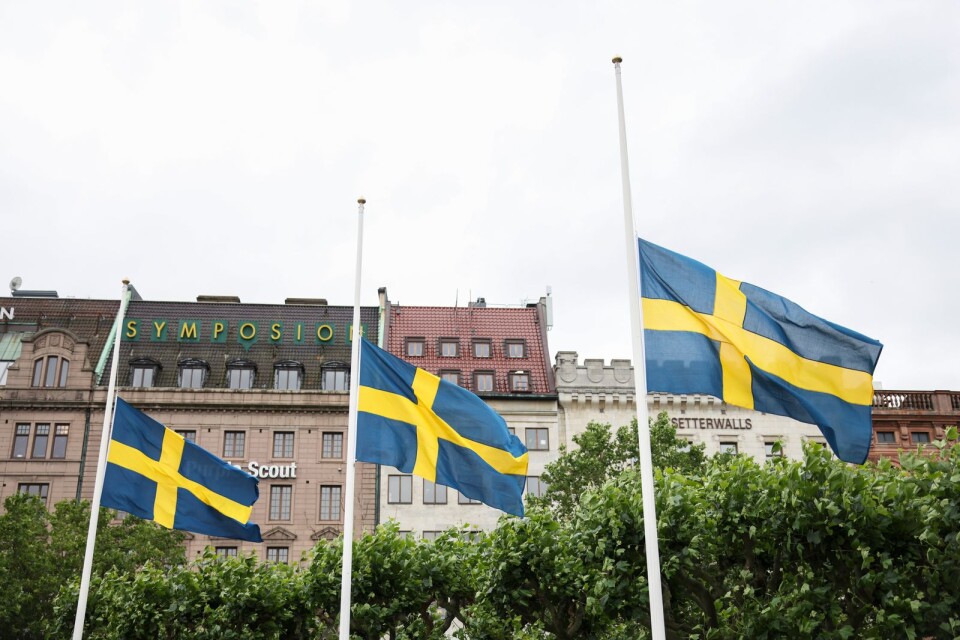 Svenska flaggan är på halvstång inför en tyst minut som hålls efter att en polis sköts till döds i Biskopsgården i Göteborg.