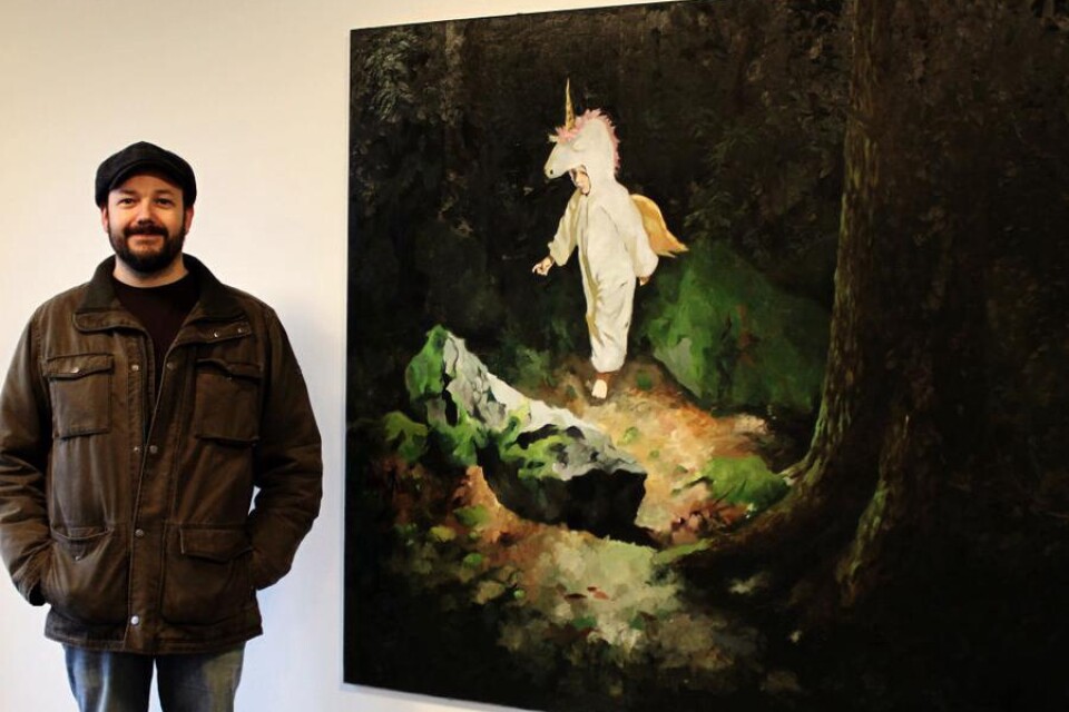 Konstnären Markus Åkesson vid en av sina tavlor i entrén, med temat Skogen.