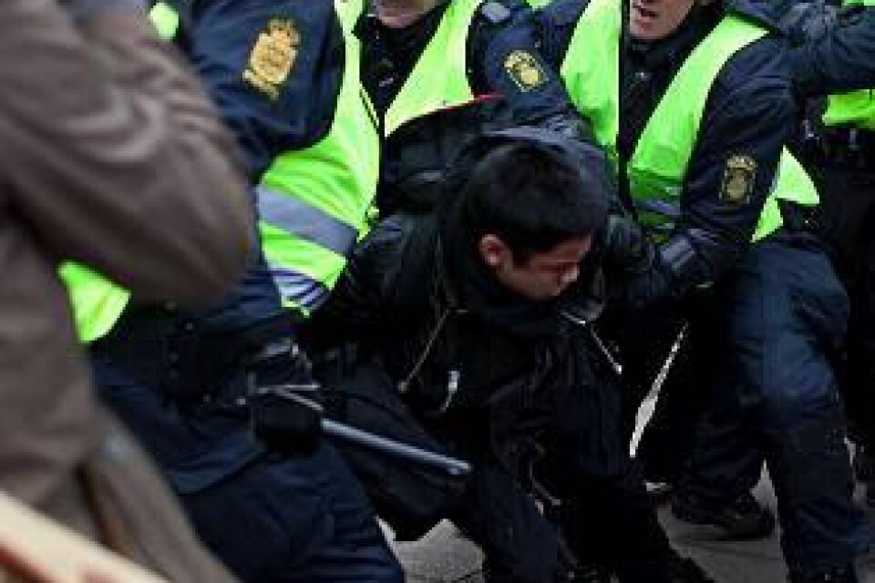 Dansk polis tar hand om en demonstrant medan pressen är där och tar bilder. Våldet utanför mötesarenan stjäl dessvärre uppmärksamhet från det som diskuteras innanför barriärerna.