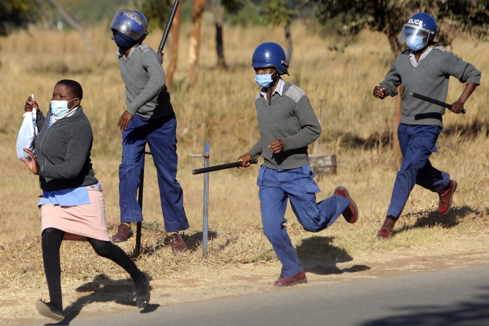 Poliser jagar en av de demonstrerande sjuksköterskorna i Zimbabwes huvudstad Harare.