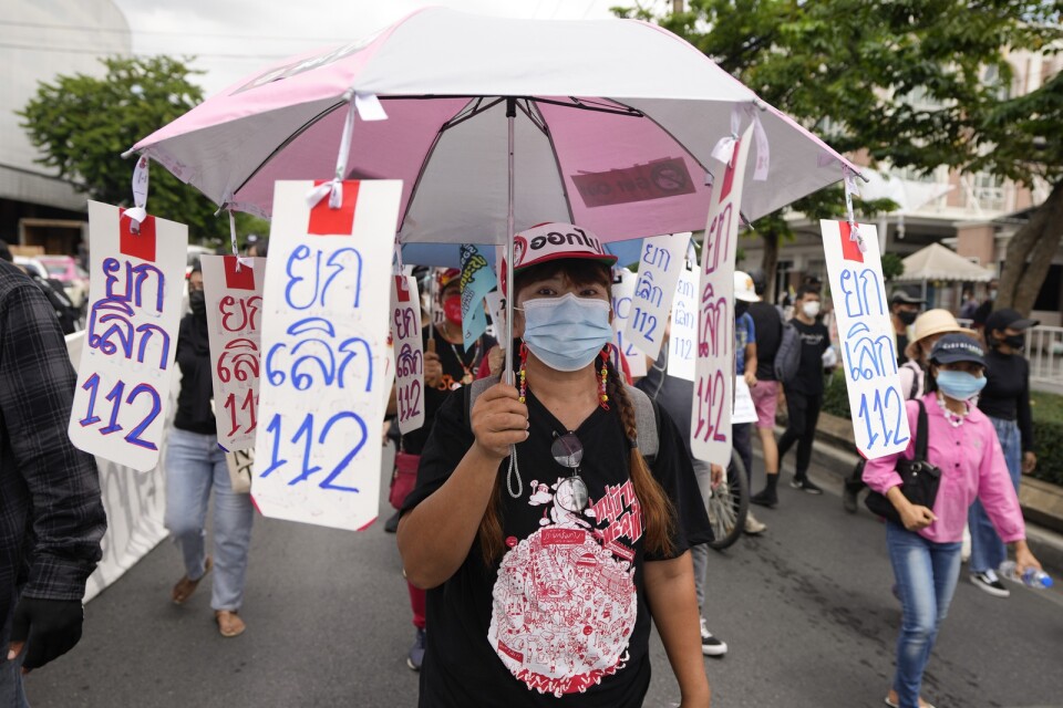 En prodemokratisk demonstrant bär skyltar med texten "nej till artikel 112", den avdelning av Thailands brottsbalk som handlar om majestätsbrott.