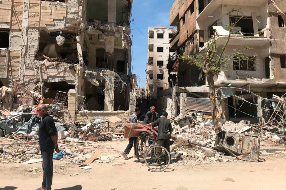 Människor står vid raserade byggnader i Douma den 16 april 2018, en dryg vecka efter klorgasattacken som dödade tiotals människor där. Arkivbild.