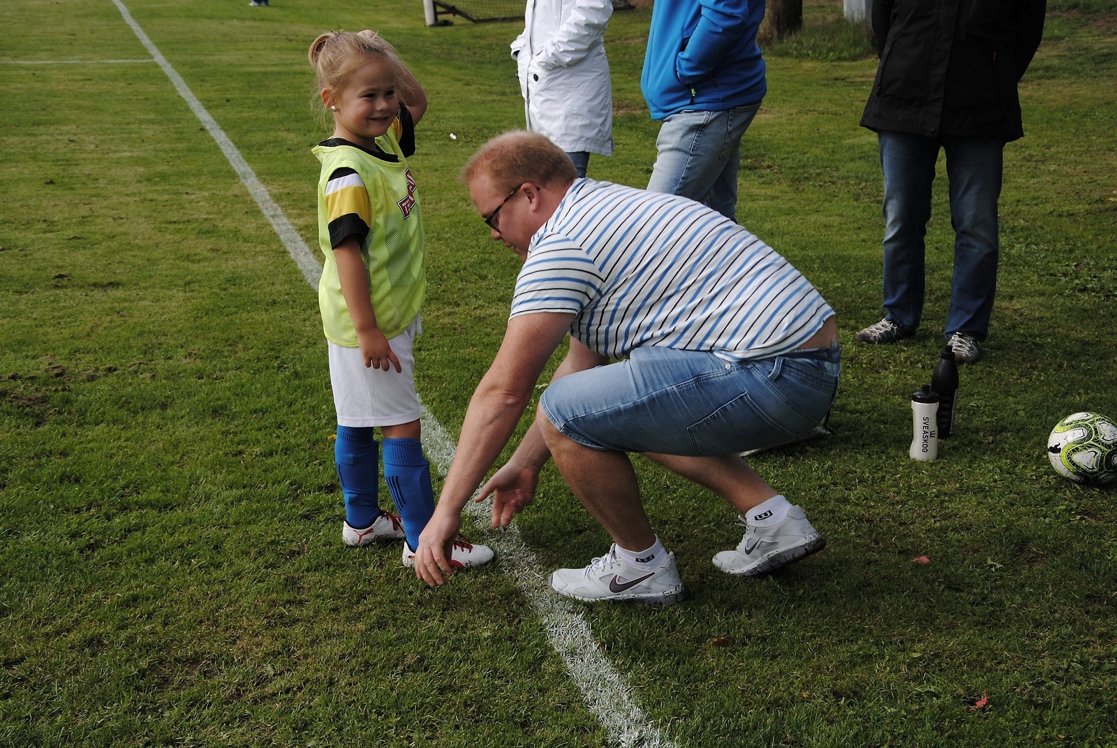 Daniel (tränare och pappa) hjälper Ella att knyta skorna.