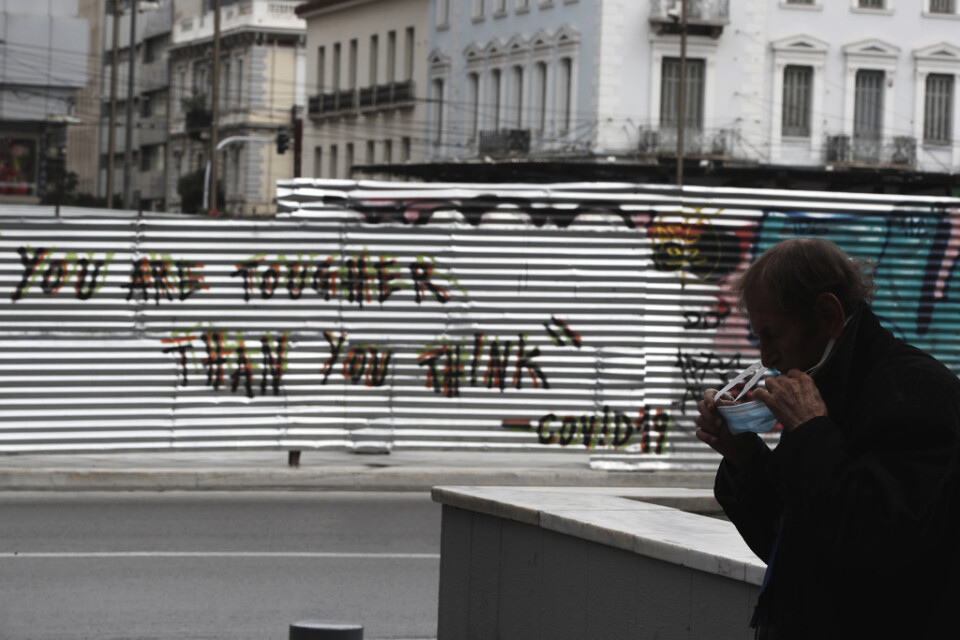 "Du är tuffare än du tror" har någon skrivit på en vägg i centrala Aten. En man som går förbli rättar till munskyddet. Arkivbild.