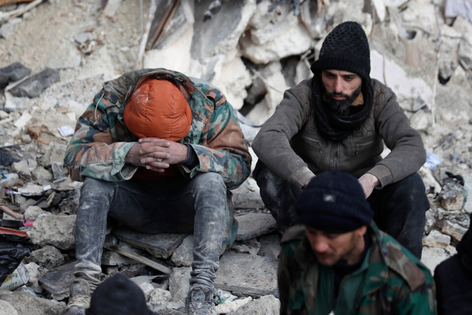 Två män pausar under räddningsarbetet i syriska Aleppo. Det krigshärjade Syrien har drabbats hårt av jordbävningskatastrofen.