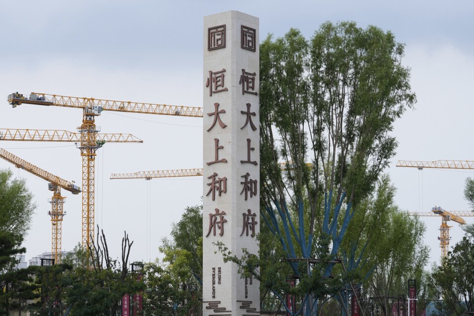 Byggkranar syns bakom en skylt med Evergrandes namn och logga vid en byggarbetsplats i Peking.