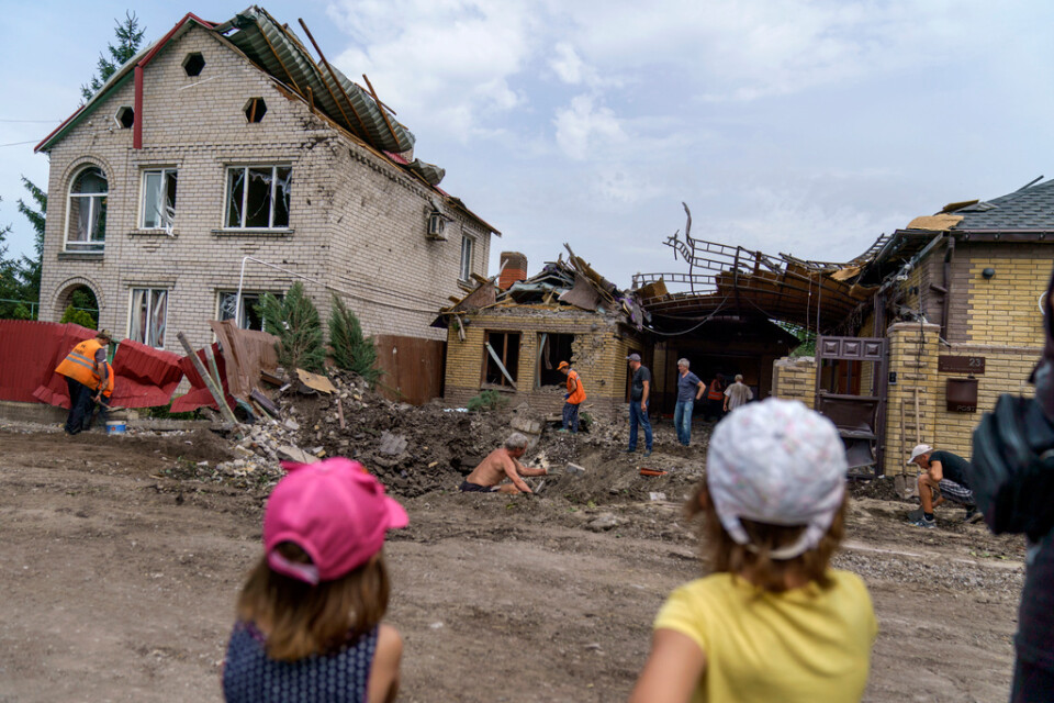 Barn ser på när räddningsmanskap går igenom skadorna efter en granatattack i Kramatorsk i östra Ukraina. Inga personer skadades i attacken i fredags.