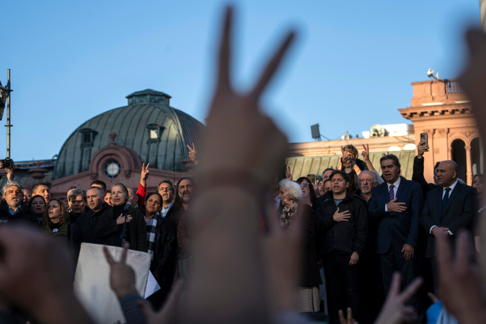 Ministrar, människorättsaktivister och sociala ledare sjunger nationalsången under en massprotest mot politiskt våld i argentinska Buenos Aires.