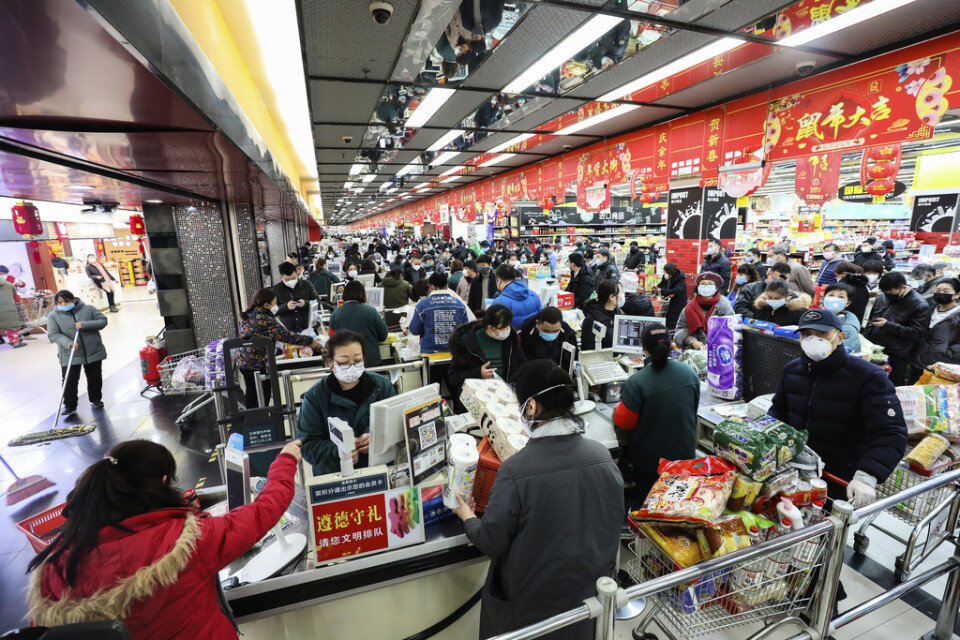 Invånare i Wuhan handlar mat med ansiktsmasker på.