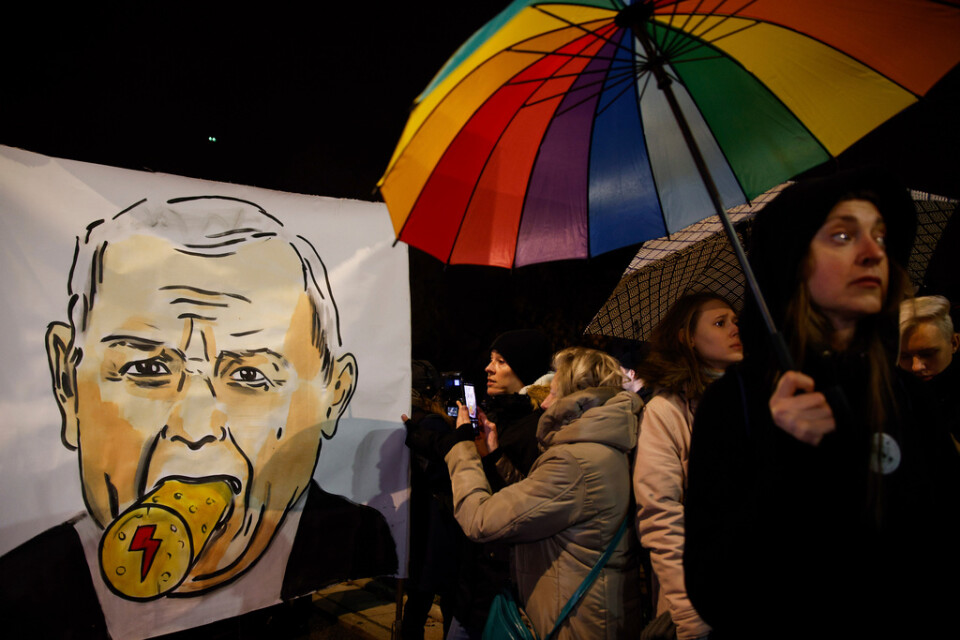 Warszawabor protesterar framför Jaroslaw Kaczynskis hus den 28 november, med en karikatyr på partiledaren där en kork pluggar igen hans mun. Kaczynski leder regeringspartiet Lag och rättvisa.
