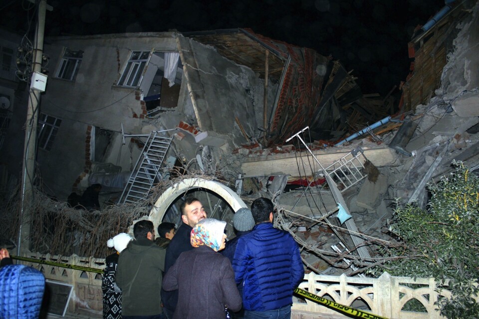 People look at a collapsed building after a 6.8 earthquake struck Elazig city centre in the eastern Turkey, Friday, Jan. 24, 2020. An earthquake with a preliminary magnitude of 6.8 rocked eastern Turkey on Friday, causing some buildings to collapse and killing at least four people, Turkish officials said. (IHA via AP)