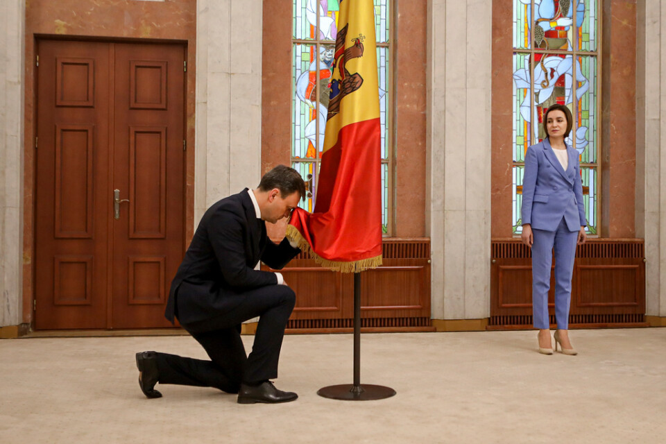 President Maia Sandu ser på när nytillträdde premiärminister Dorin Recean bugar inför den moldaviska flaggan den 16 februari. Recean fick posten för att hantera det ökade säkerhetshotet.