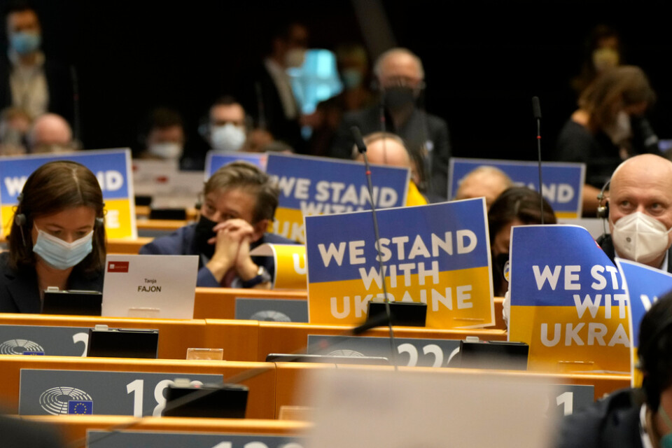 Ledamöter i EU-parlamentet visar sitt stöd för Ukraina under tisdagens extrainsatt debatt i Bryssel.