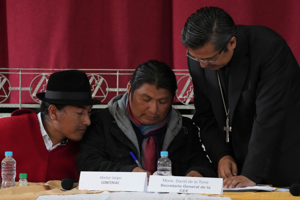 Ledarna för ursprungsbefolkningens proteströrelse, Leonidas Iza (vänster) och Marlon Vargas (mitten) granskar överenskommelsen med regeringen. Till höger står den katolska prästen David de la Torre, som har medlat fram avtalet.