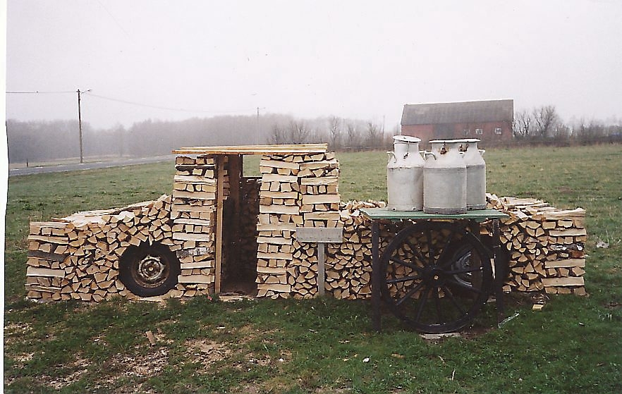En lastbil med gamla tiders mjölkkannor vid ett mjölkbord försett med vagnshjul. Detta är ett av Ruben Axelsons många konstverk av vedträ. Foto: Ruben Axelson