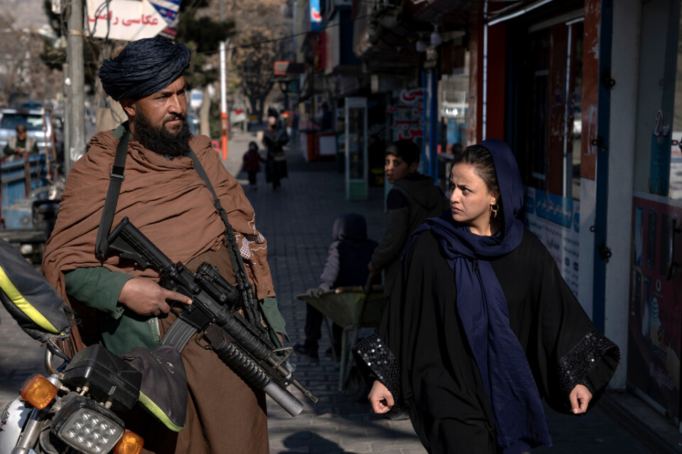 En väpnad taliban patrullerar i Kabul när en kvinna promenerar förbi. Bilden togs den 26 december förra året.