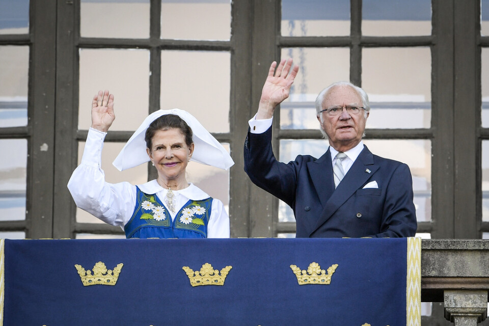 Drottning Silvia och kung Carl XVI Gustaf på Logården framför Stockholms slott i samband med nationaldagsfirandet.