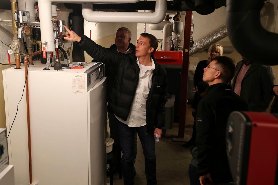 Jerker Nilsson kontrollerar effekten i en av värmepumparna som är installerade i källaren. I bakgrunden syns Ingela Ekelund, verksamhetschef på Solbacken.