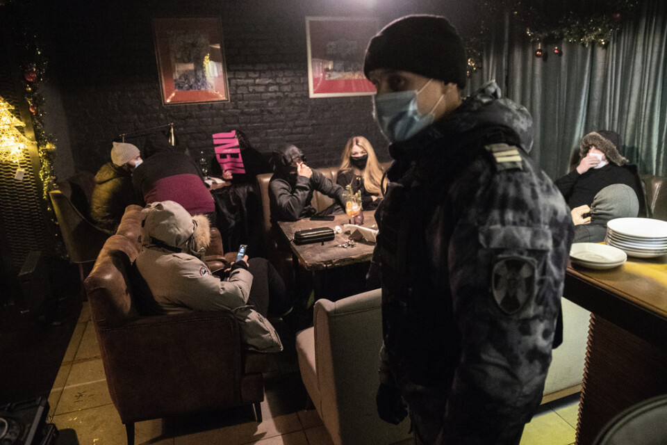 En polis inspekterar en bar i Moskva som brutit mot lokala restriktioner under julhelgen. Bilden är från den 26 december.