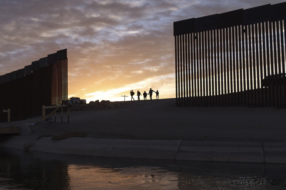 Migranter vid en lucka i metallbarriär längs med gränsen mellan USA och Mexiko, den 10 juni.