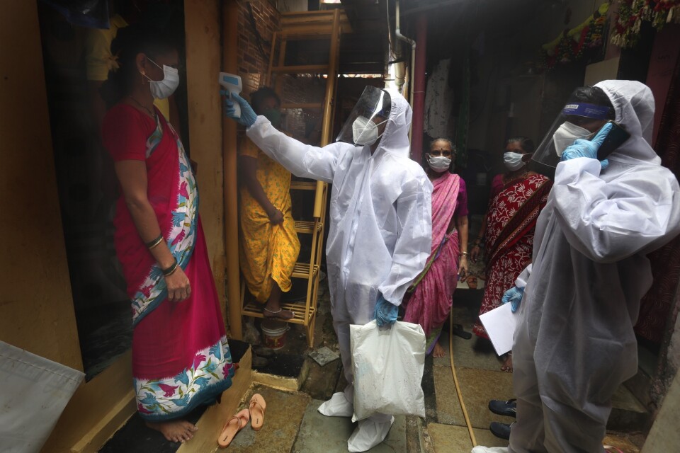 En vårdarbetare tar temperaturen på en kvinna i ett slumområde i indiska Bombay (Mumbai) i slutet av juni.