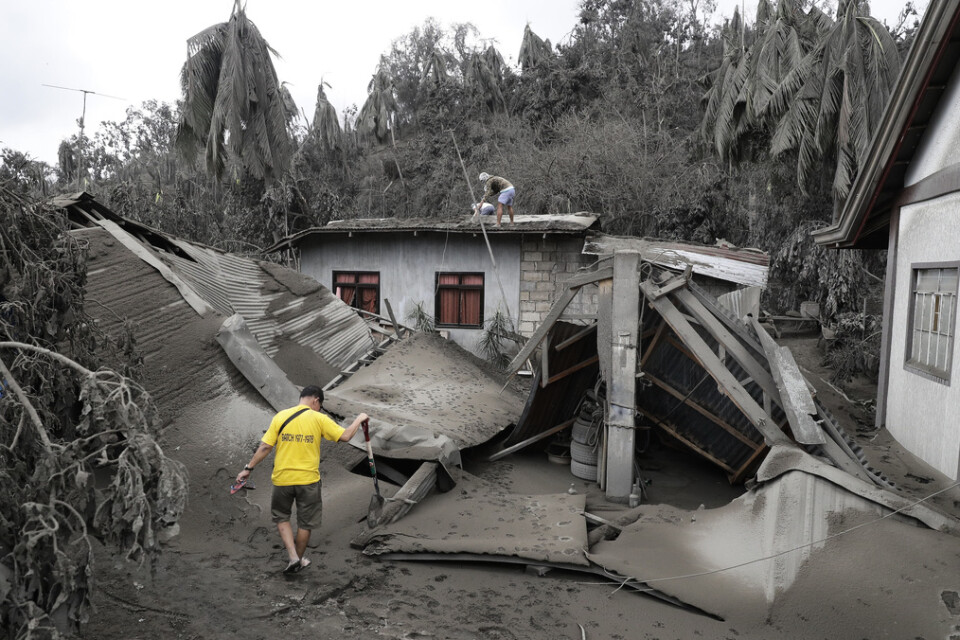 Invånare vid ett hus som förstörts av vulkanaska i södra Filippinerna.