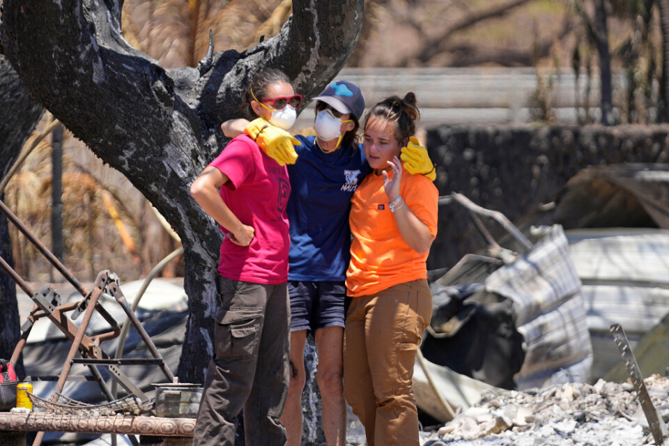 Tre kvinnor kramas efter att ha grävt i ruinerna efter sitt hem i Lahaina i Hawaii.