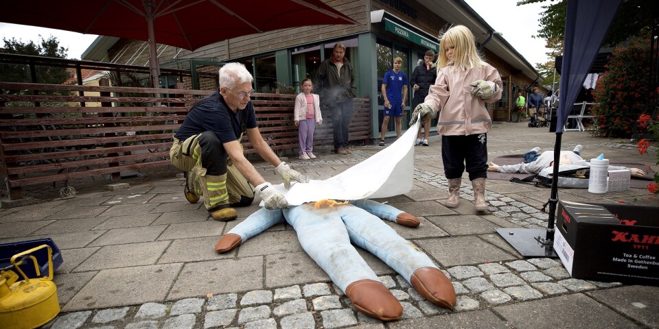 Jörgen Palmqvist, styrkeledare vid räddningstjänsten i Viskafors, visar Jessi Bohman, 5 år, hur en brand på en människa ska släckas.Det var ett av inslagen på Viskaforsdagen.
