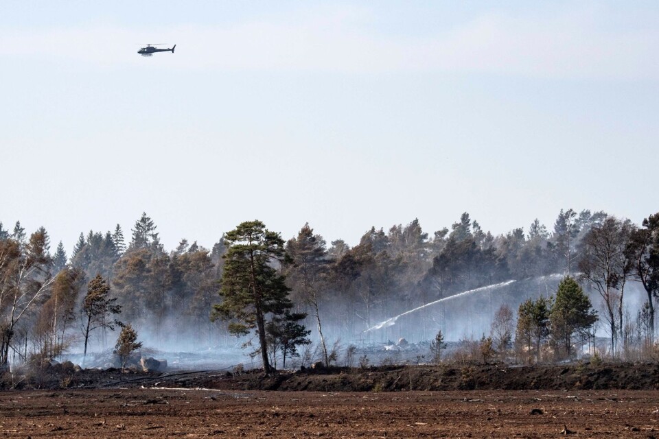 A helicopter looks over the burning ground at Åbuamosse outside Hästveda on Wednesday.