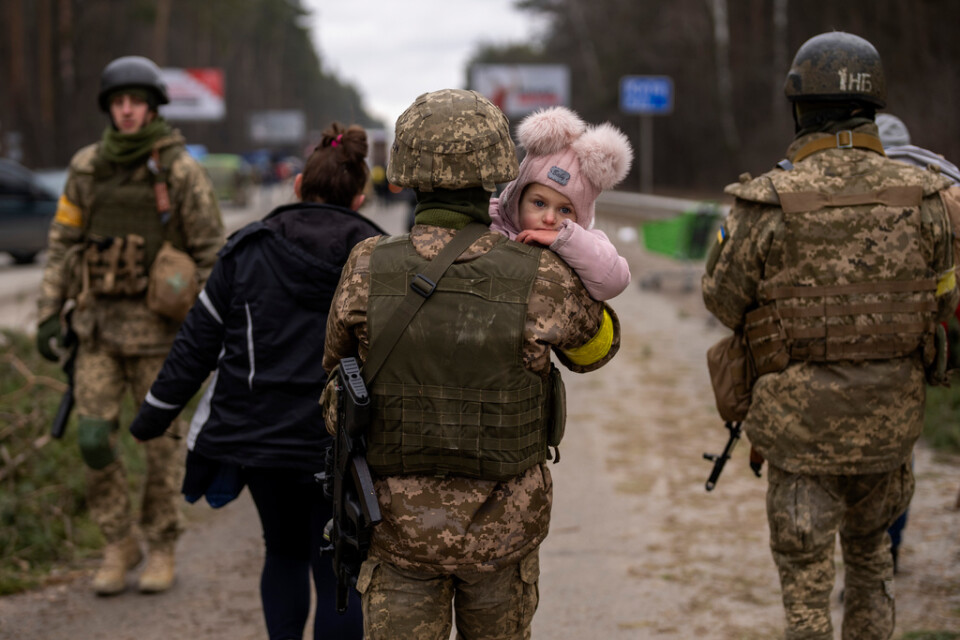 En ukrainsk soldat hjälper en familj att fly staden Irpin under lördagen.