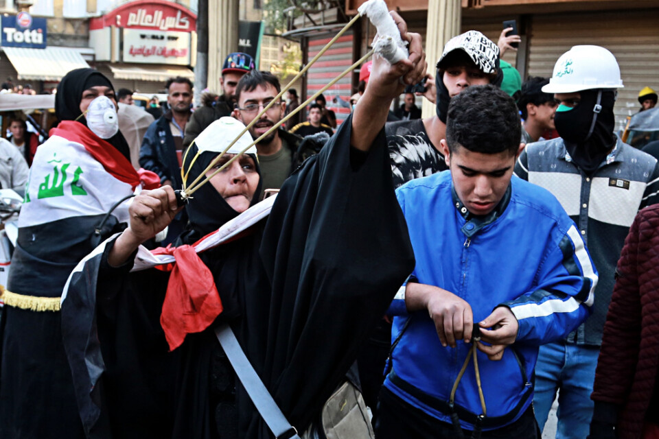 En kvinna spänner en slangbella vid protester i Iraks huvudstad Bagdad på torsdagen.