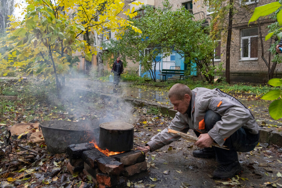 En man i staden Bachmut i Donetskregionen lagar mat utomhus i närheten av sitt hem.