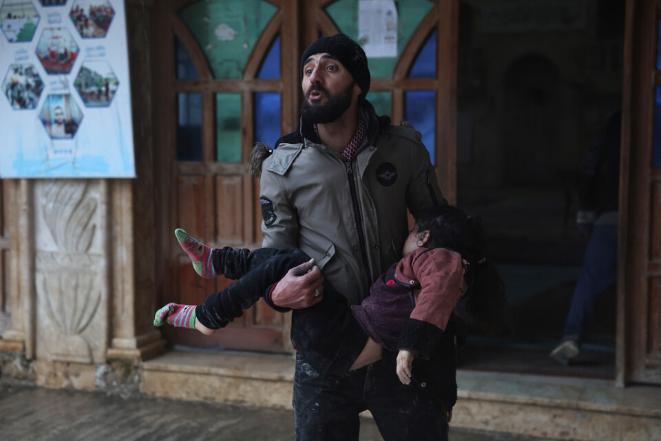En man i syriska Azmarin bär på ett offer för jordbävningen. Hundratals syrier har omkommit.