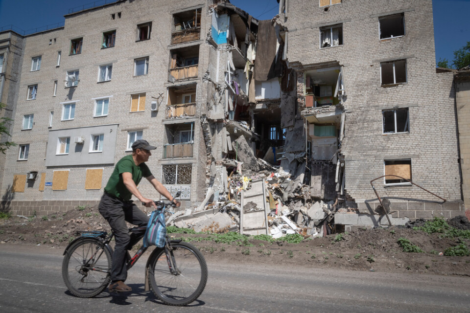 En man cyklar förbi en skadad byggnad i Bachmut. Arkivbild.