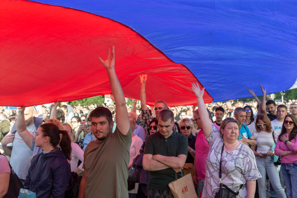 Demonstranter håller upp den serbiska flaggan under en massprotest mot regeringen i huvudstaden Belgrad på lördagen.