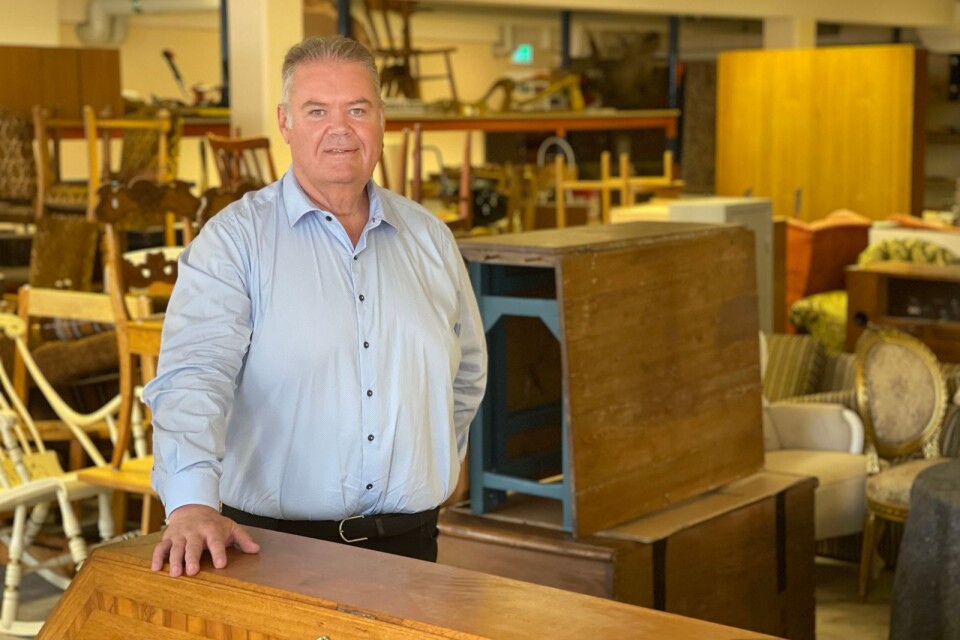 Johan Andersson omgiven av gamla möbler som söker nya ägare.