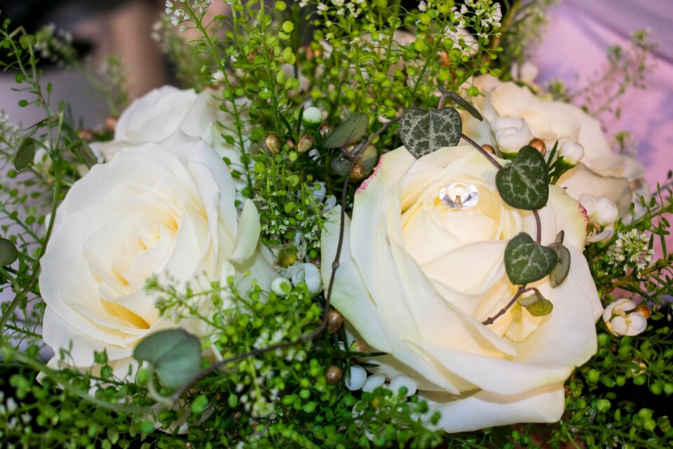 Denna brudbukett består av vita rosor, vaxblomma och thalspi. Dessutom har Pia satt i pärlor och ringlat en bit av växten ”hjärta på tråd” över rosorna.
