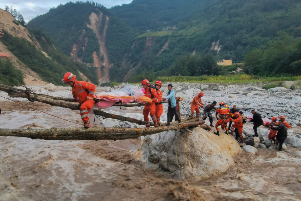 Räddningsarbetare hjälper en överlevande över floden i historiska staden Moxi i jordbävningsdrabbade Sichuanprovinsen.