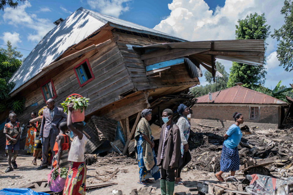 Människor bredvid ett förstört hus i en by i provinsen Södra Kivu i östra Kongo-Kinshasa.