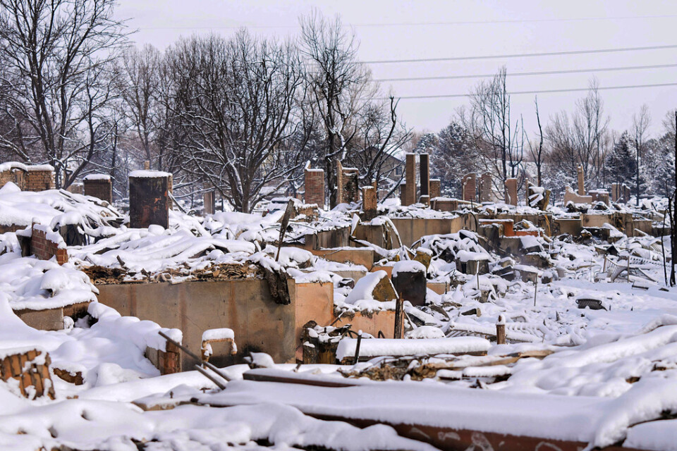 Snö täcker resterna av hus på en gata i Louisville i Colorado i USA.