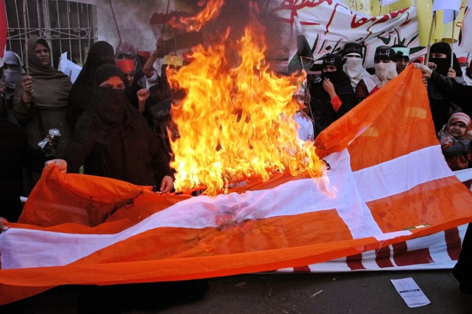 Den danska flaggan antänds under en demonstration i Lahore i Pakistan den 24 februari 2006, i raseri mot Jyllands-Postens publicering av karikatyrer på profeten Muhammed. Arkivbild.