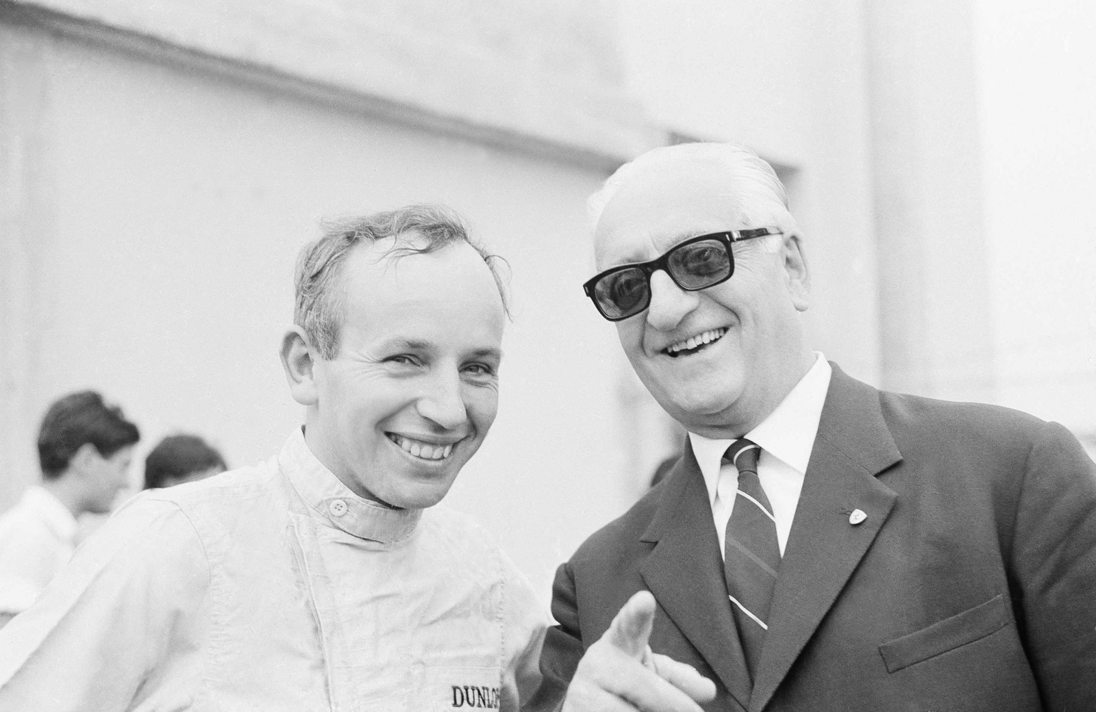 Det brittiska racerässet John Surtees (till vänster) och biltillverkaren Enzo Ferrari strålar ikapp en tävlingsdag år 1964 på racerbanan Monza i Italien. Samma år körde John Surtees modellen 158 F1 och blev världsmästare i formel 1.
Foto: AP/TT