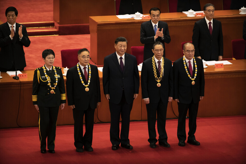 Kinas president Xi Jinping, i mitten, tillsammans med medicinska experter under ceremonin i Folkets stora hall i Peking på tisdagen.