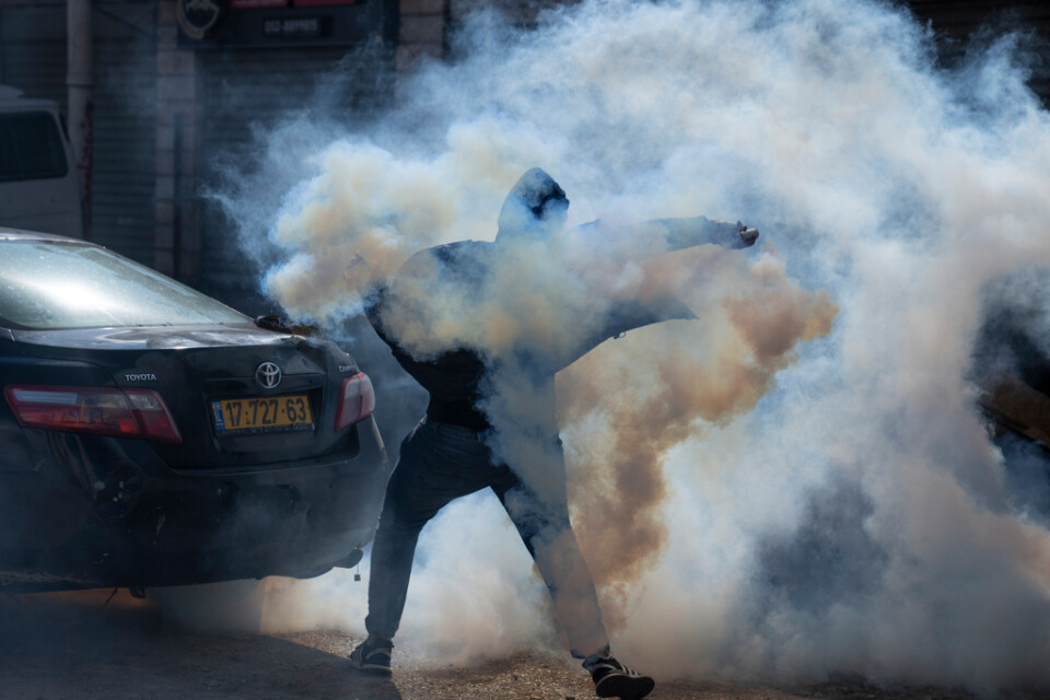 En palestinsk demonstrant kastar tillbaka en tårgasbehållare mot israeliska soldater i en drabbning den 27 december. Arkivbild.