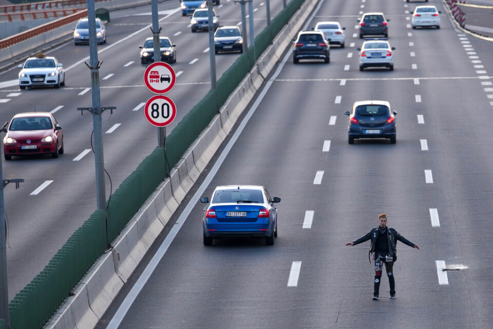 En man försöker blockera en motorväg under fredagens protester i Serbiens huvudstad Belgrad.