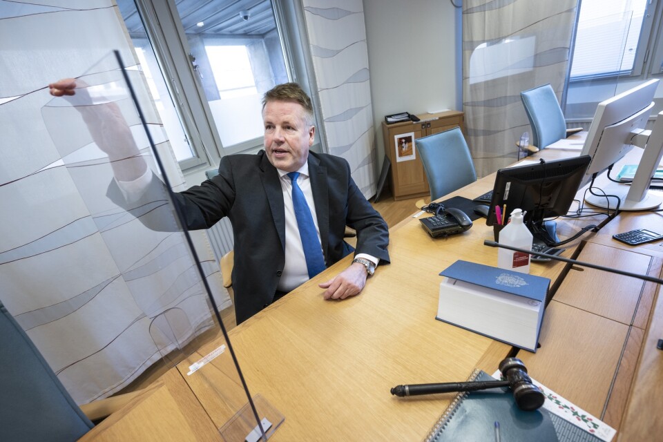 Lennart Strinäs, tillförordnad lagman i Malmö tingsrätt, visar de plexiglas som monterats mellan sittplatserna i en av rättssalarna i Malmö tingsrätt för att förhindra smittspridning på domarpodiet.