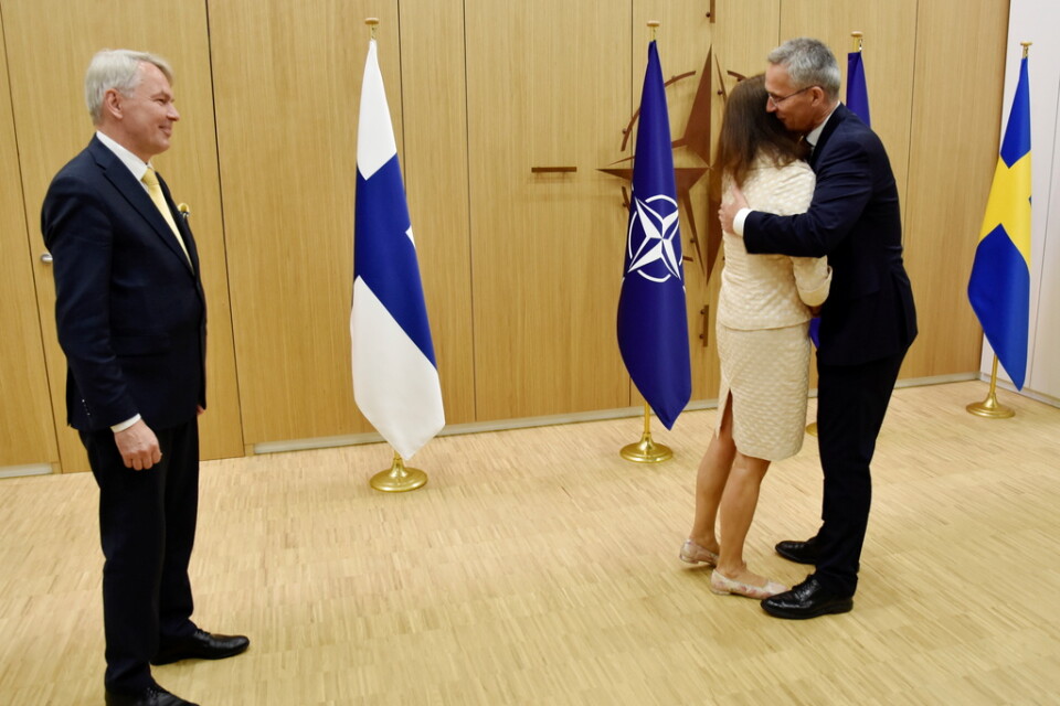 Finlands utrikesminister Pekka Haavisto ser på när Natochefen Jens Stoltenberg välkomnar Sveriges utrikesminister Ann Linde med en kram i Bryssel.