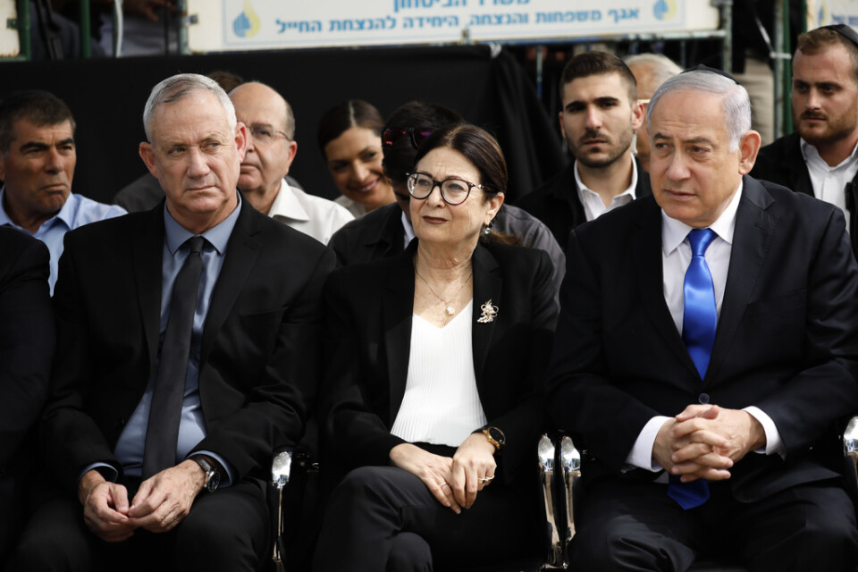 Oppositionsledaren Benny Gantz till vänster i bild och premiärminister Benjamin Netanyahu till höger, med Esther Hayut, chefsdomare i Israels högsta domstol, emellan sig. Arkivbild.