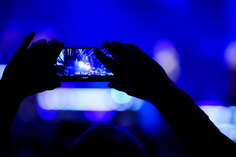 Ett fan håller upp en mobiltelefon under torsdagens hyllningskonsert till Aviciis minne på Friends arena.
